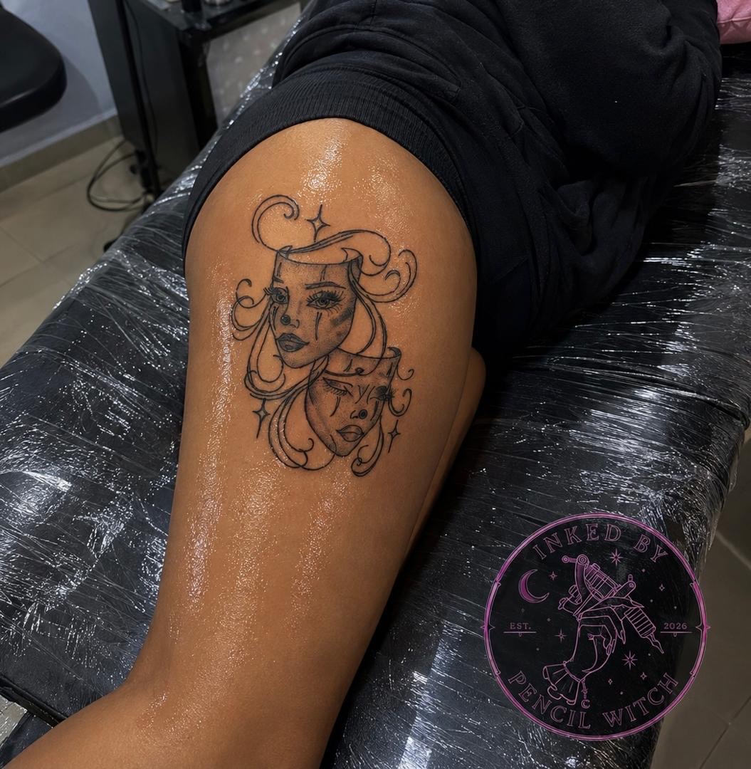Two-faced harlequin tattoo on thigh — comedy and tragedy masks intertwined