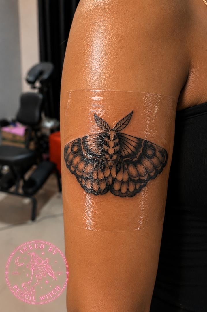 Detailed moth tattoo with intricate wing patterns on upper arm