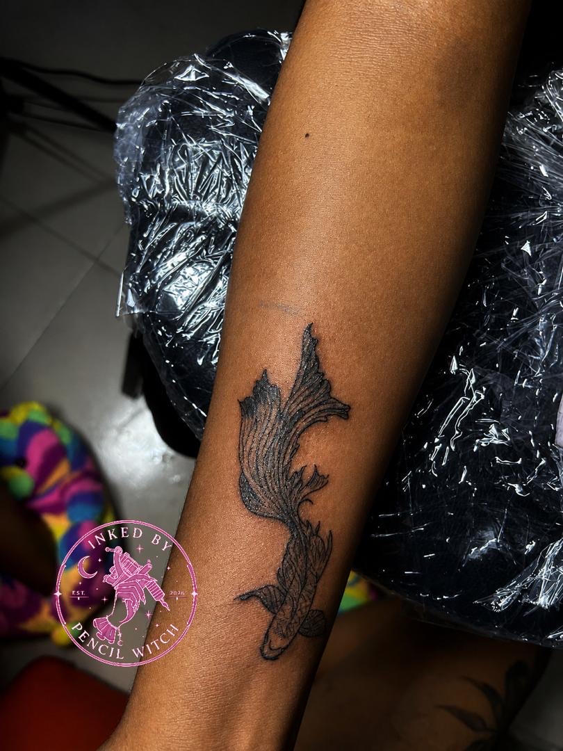 Black and grey koi fish tattoo on inner forearm