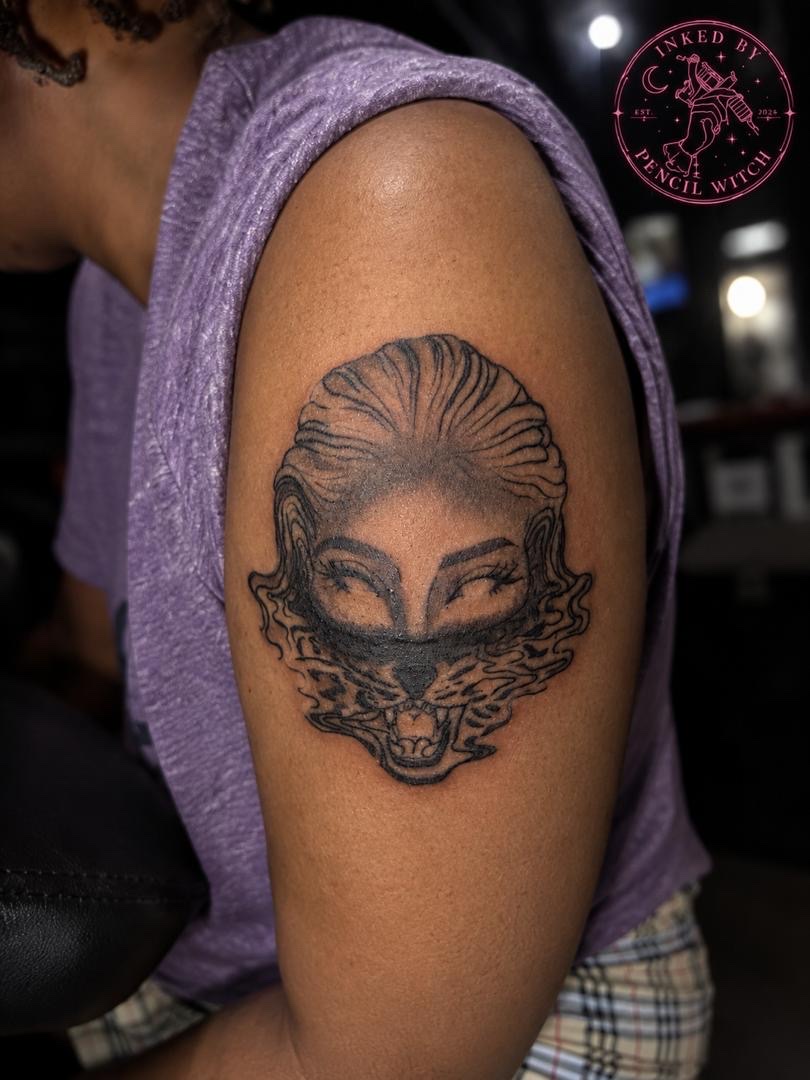 Surreal tattoo blending feminine eyes with a roaring tiger on the shoulder