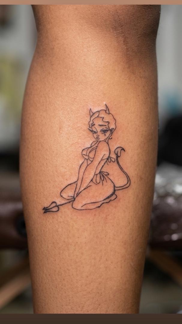 Line-art devil pinup tattoo on a calf